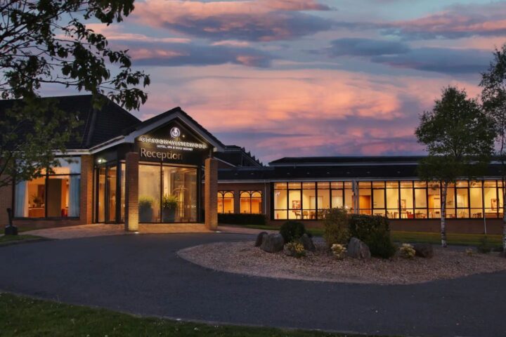 Illuminated entrance of Glasgow Westerwood Hotel, Spa & Golf Resort at dusk.